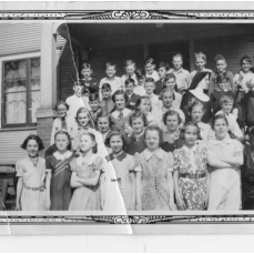 Marian shown in St. John's elementary school class with Sister Joanella (sp?). Marian 3rd from left in the bottom (1st) row and is standing between Tunnie Kelly and June Frieberger - Bill Rammer
