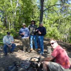 Mike is sitting on the left in a group picture. This picture taken after he helped prepare a great shore lunch in Canada of freshly caught Walleye. - PTO
